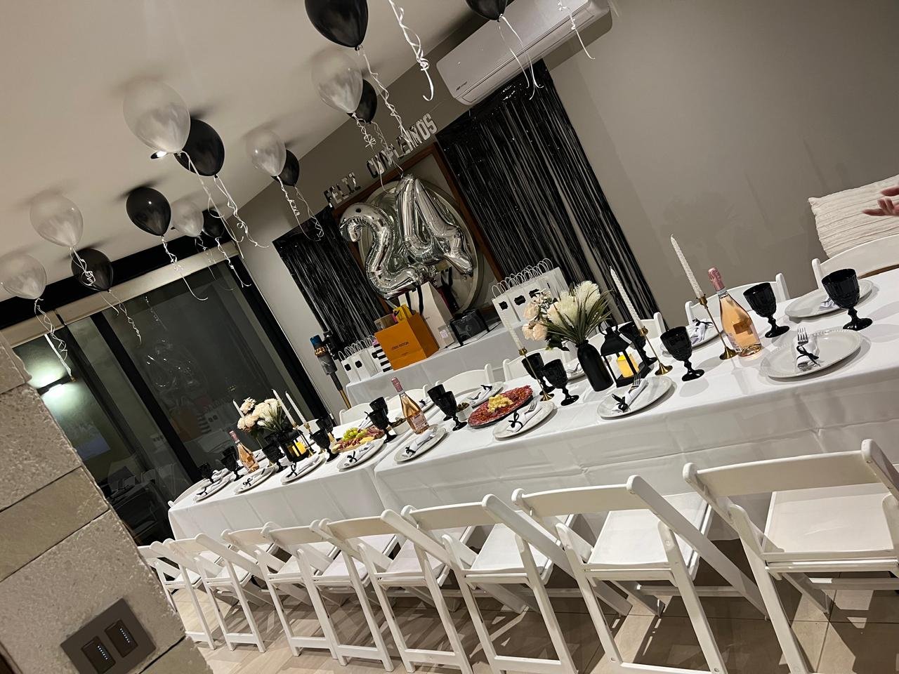 Decoración de cumpleaños elegante con mesa larga, globos blancos y negros, copas negras y montaje para cumpleaños en Querétaro.